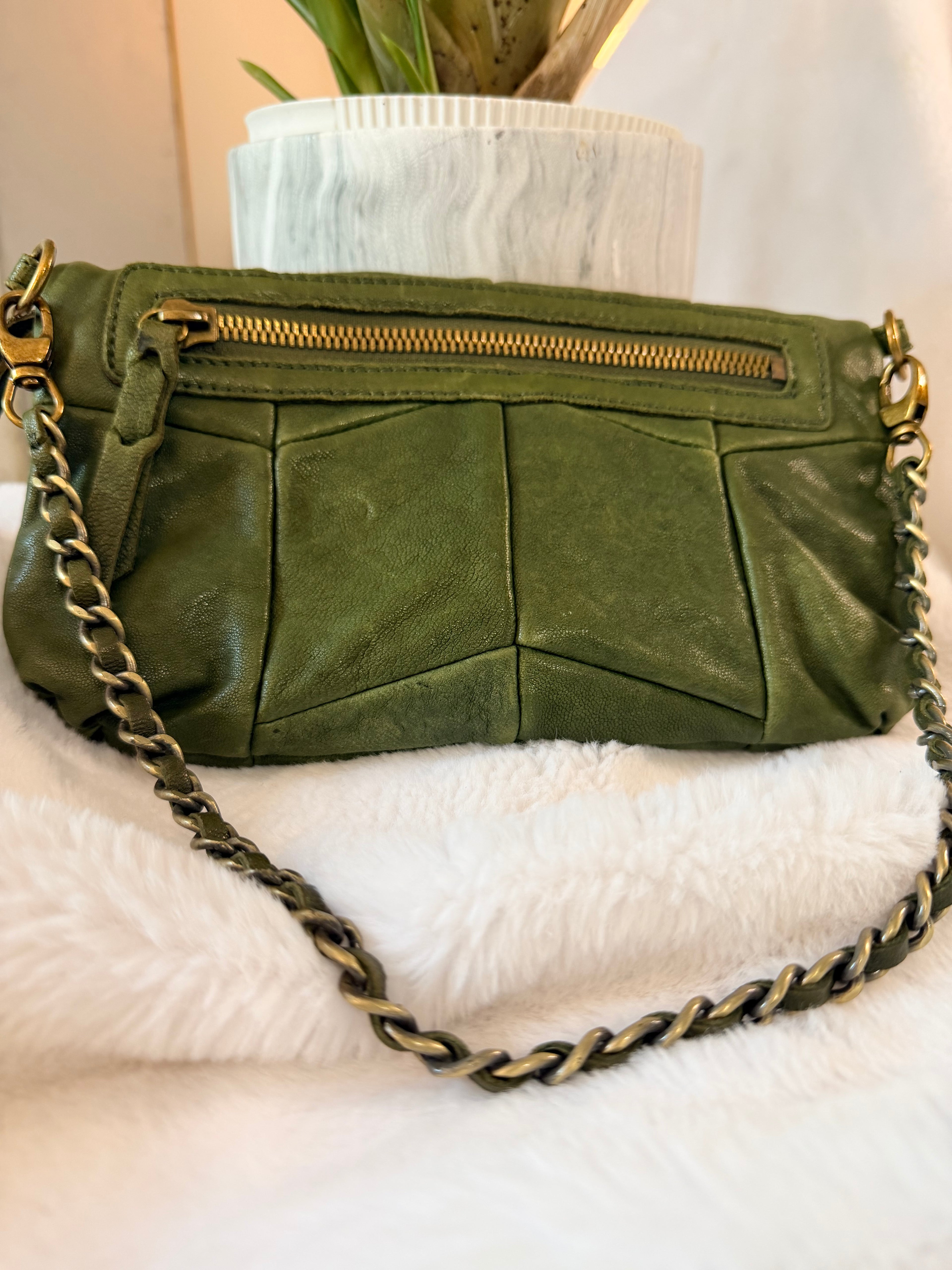 Green leather handbag with gold chain strap on a white surface